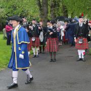 Town Crier John Raphael leads the parade. Followed by the Cheltenham Pipe Band