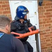 IMPACT: An officer uses an enforcer to break open a door in Evesham