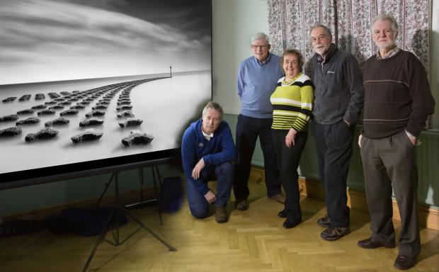Evesham Journal: The Monochrome Gold Medal winning image &quot;Sweeping&quot; by Justin Minns from Suffolk. Alongside the screen are the panel of selectors from left to right: Leigh Preston, David Gibbins, Margaret Salisbury, John Chamberlin and Peter Preece.