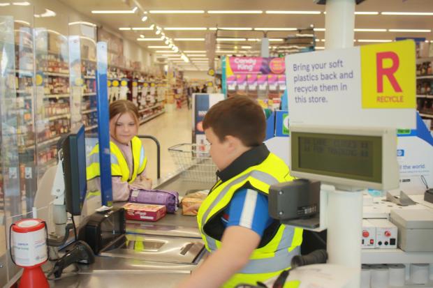 Excited youngsters get to try out working behind the tills at supermarket